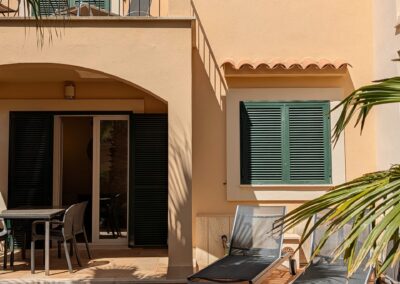 Überdachte Terrasse des Ferienhauses mit Esstisch und zwei Sonnenliegen im Schatten