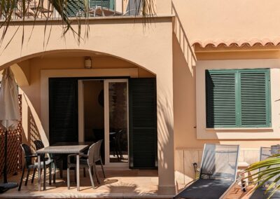 Private Terrasse mit Esstisch, Sonnenliegen und grünen Fensterläden