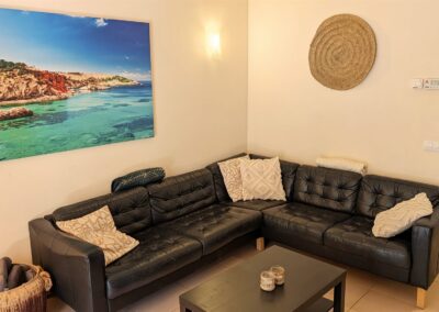 Wohnzimmer des Ferienhauses mit Ledercouch und großem Meeresbild an der Wand