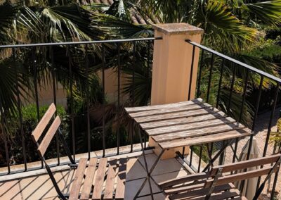 Balkon des Ferienhauses mit Bistro-Set zwischen Palmen
