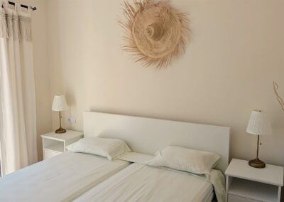 Helles Schlafzimmer mit Doppelbett und Zugang zum Balkon