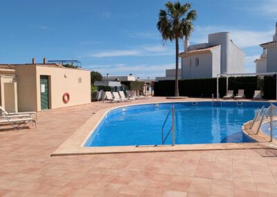 Poolbereich mit Sonnenliegen und Palme an der Wasserkante